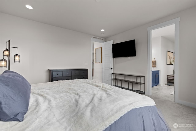 bedroom featuring light colored carpet and ensuite bath