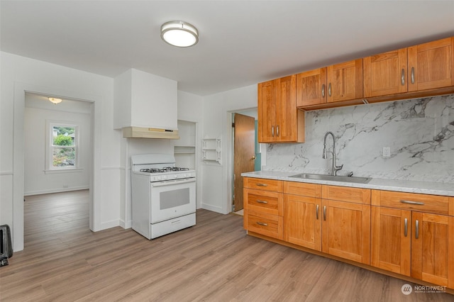 kitchen with sink, white gas range oven, range hood, tasteful backsplash, and light hardwood / wood-style floors