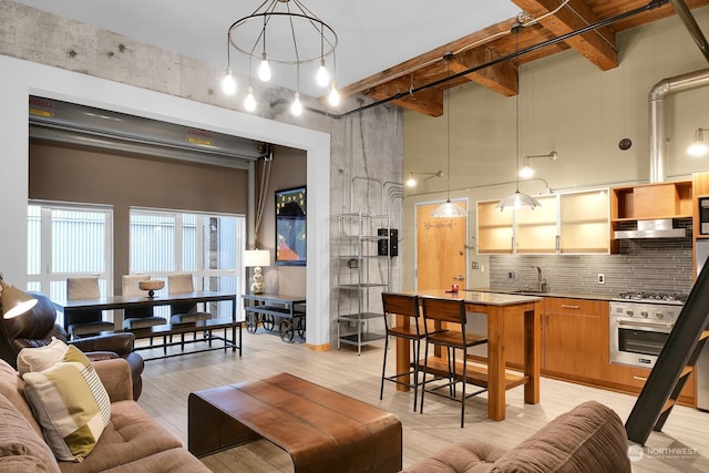 living room with sink, beamed ceiling, light hardwood / wood-style floors, and a notable chandelier