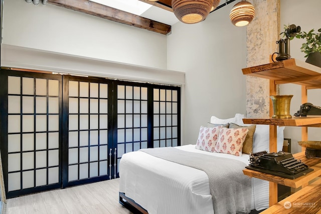 bedroom featuring beam ceiling and light hardwood / wood-style flooring