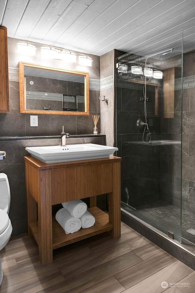 bathroom with an enclosed shower, toilet, vanity, tile walls, and hardwood / wood-style flooring