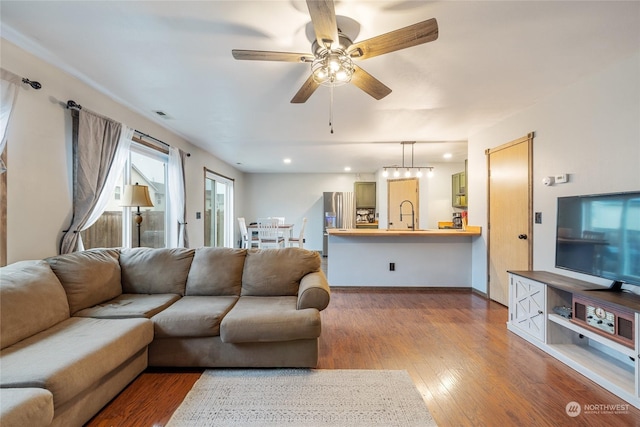 living room featuring hardwood / wood-style flooring, ceiling fan, and sink