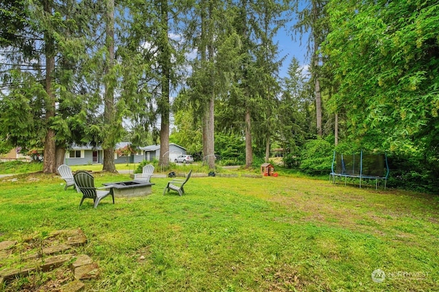 view of yard with a fire pit and a trampoline