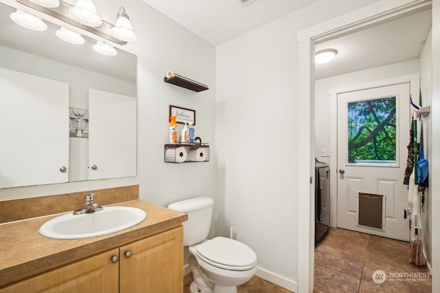 bathroom featuring toilet, vanity, and washer / dryer