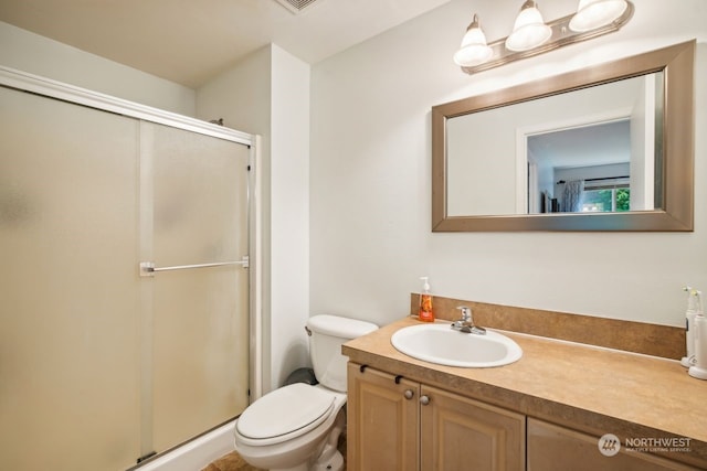 bathroom with an enclosed shower, vanity, and toilet