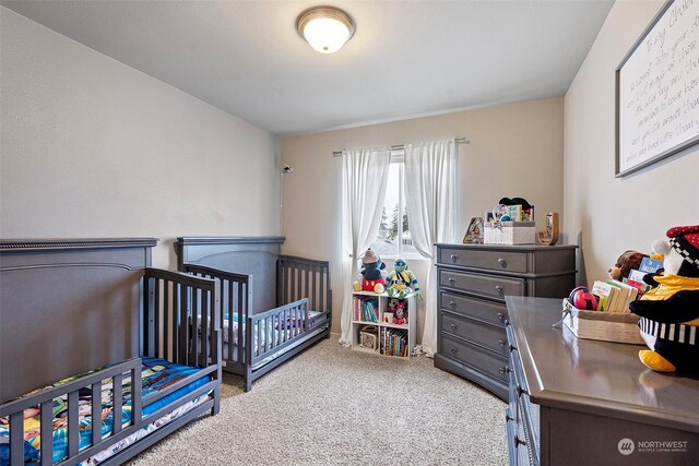 carpeted bedroom featuring a nursery area