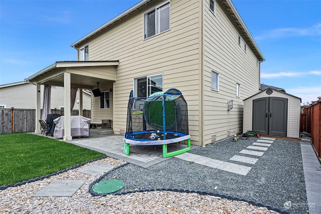 rear view of property featuring a patio, a shed, and a trampoline