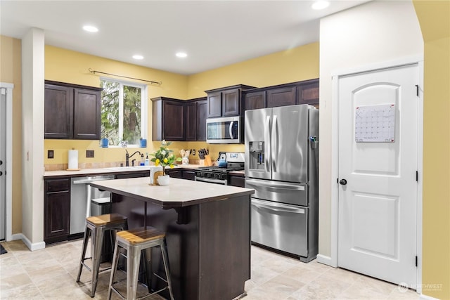 kitchen featuring sink, a breakfast bar, a kitchen island, dark brown cabinets, and appliances with stainless steel finishes