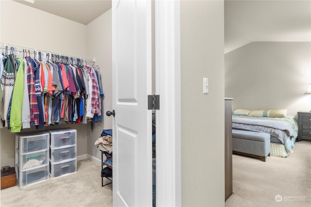 spacious closet featuring light colored carpet and lofted ceiling