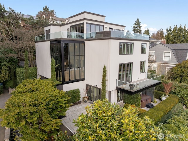 back of property featuring a balcony and stucco siding