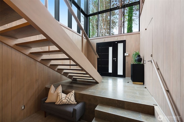 foyer featuring wood walls and a towering ceiling