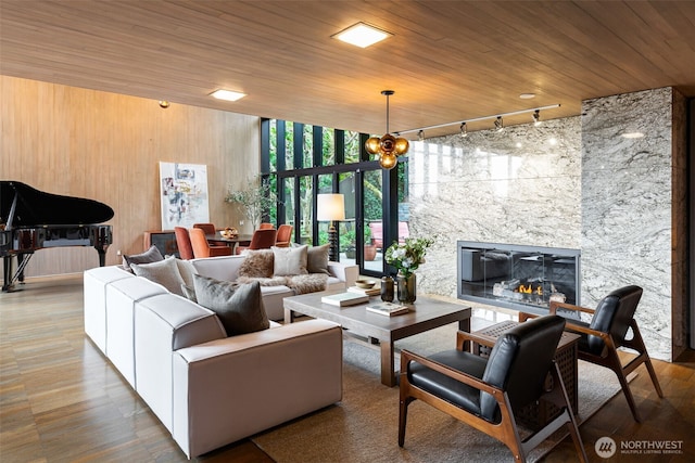 living room featuring wooden ceiling, a wall of windows, wood walls, a fireplace, and track lighting