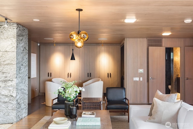 living room with wood walls, wooden ceiling, and wood finished floors