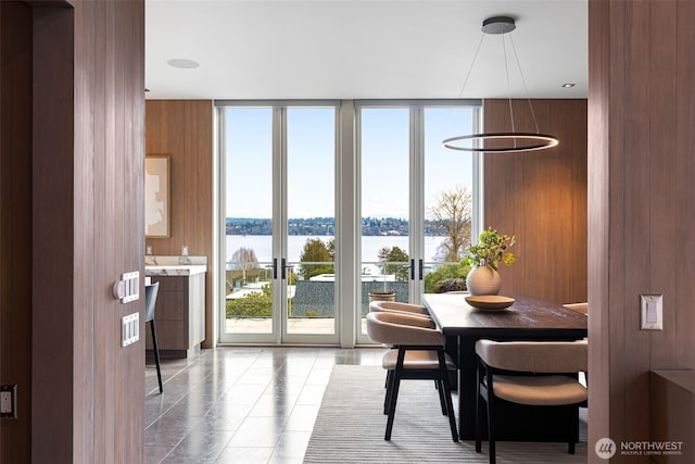 dining room with a water view, light tile patterned floors, and a wall of windows