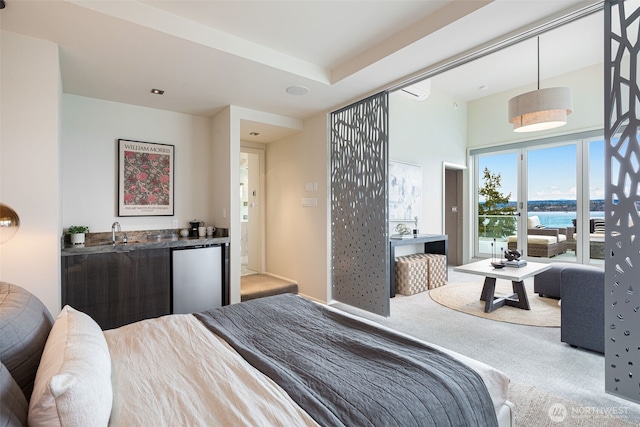 carpeted bedroom featuring a water view, wet bar, a sink, and refrigerator