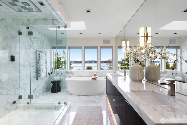 full bathroom with a water view, a sink, marble finish floor, a soaking tub, and double vanity