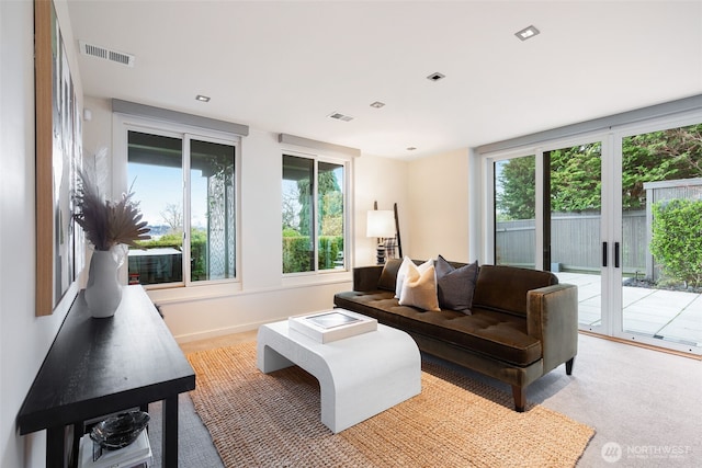 living room with baseboards, visible vents, and light colored carpet