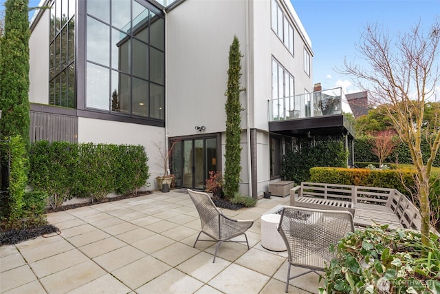 back of property with a patio area, a balcony, and stucco siding