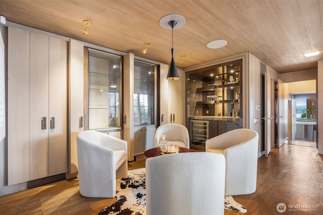 sitting room featuring a wealth of natural light, wooden ceiling, indoor wet bar, and wood finished floors