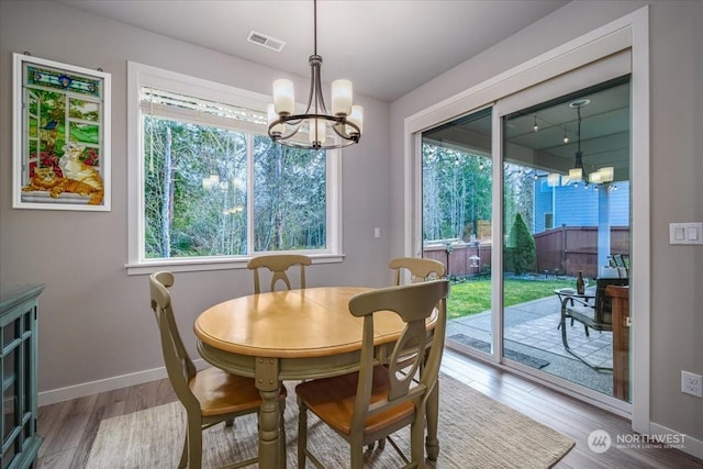 dining area featuring a notable chandelier, a wealth of natural light, and light hardwood / wood-style flooring