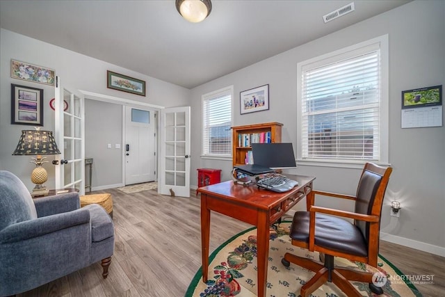 home office with plenty of natural light, light hardwood / wood-style flooring, and french doors