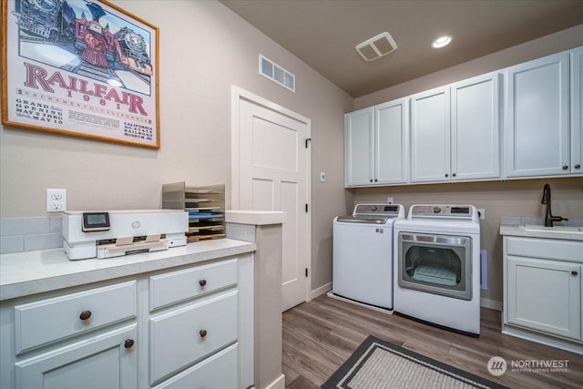 laundry area with light hardwood / wood-style floors, washer and clothes dryer, and sink