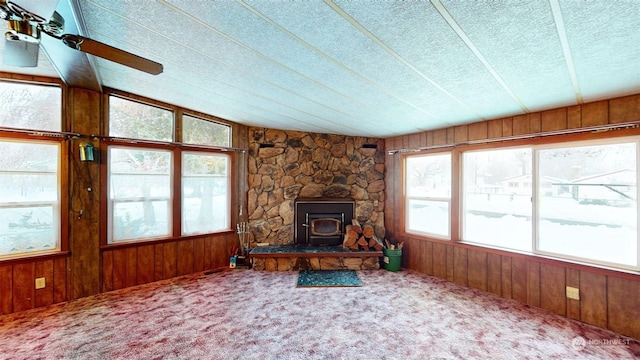 unfurnished living room featuring carpet, a wood stove, and wooden walls