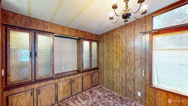 interior space with a wealth of natural light, wooden walls, and a chandelier