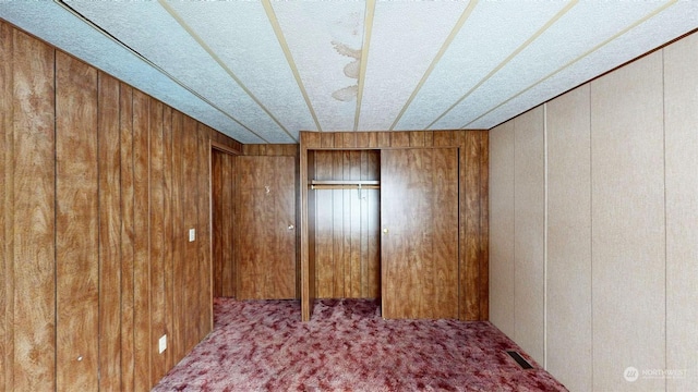 unfurnished room featuring carpet floors and wooden walls