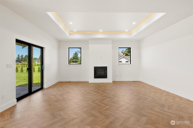 unfurnished living room with a raised ceiling and light parquet flooring