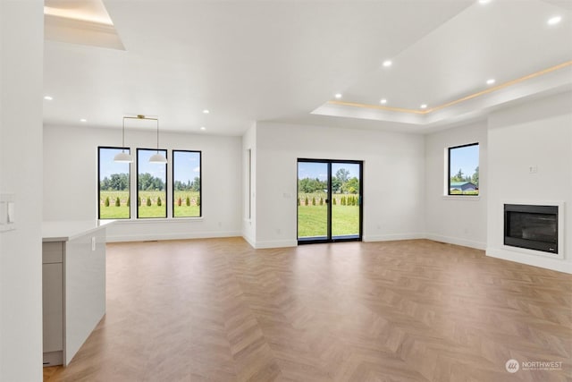 unfurnished living room featuring a raised ceiling and light parquet flooring