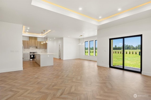 unfurnished living room with a raised ceiling, light parquet flooring, and crown molding