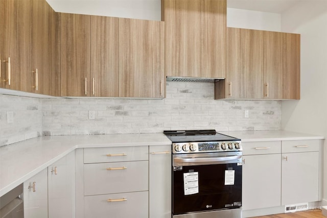 kitchen featuring white cabinetry, wall chimney exhaust hood, electric range, and decorative backsplash