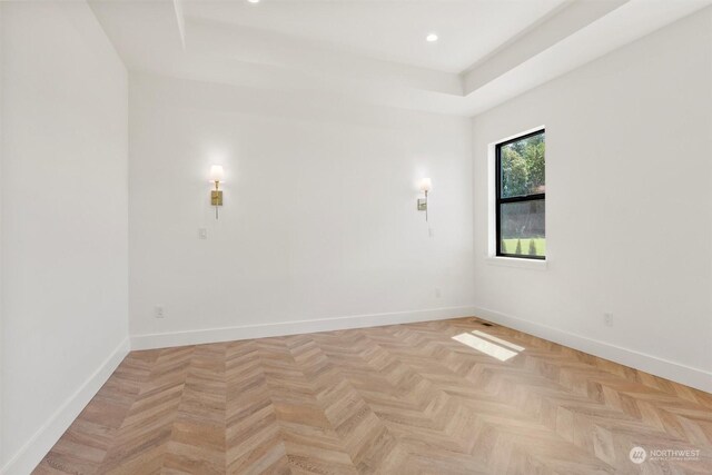 spare room featuring a tray ceiling and light parquet floors