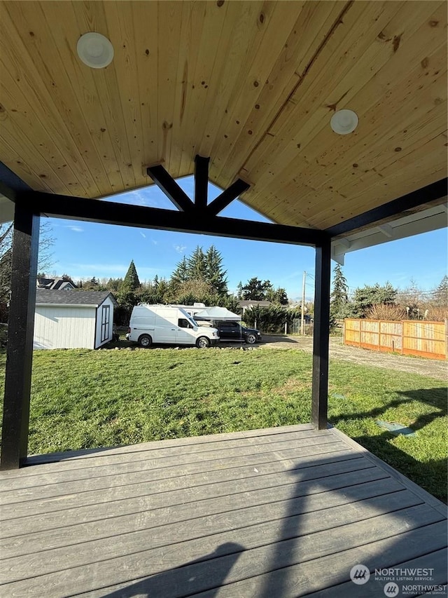 wooden terrace with a storage shed and a yard