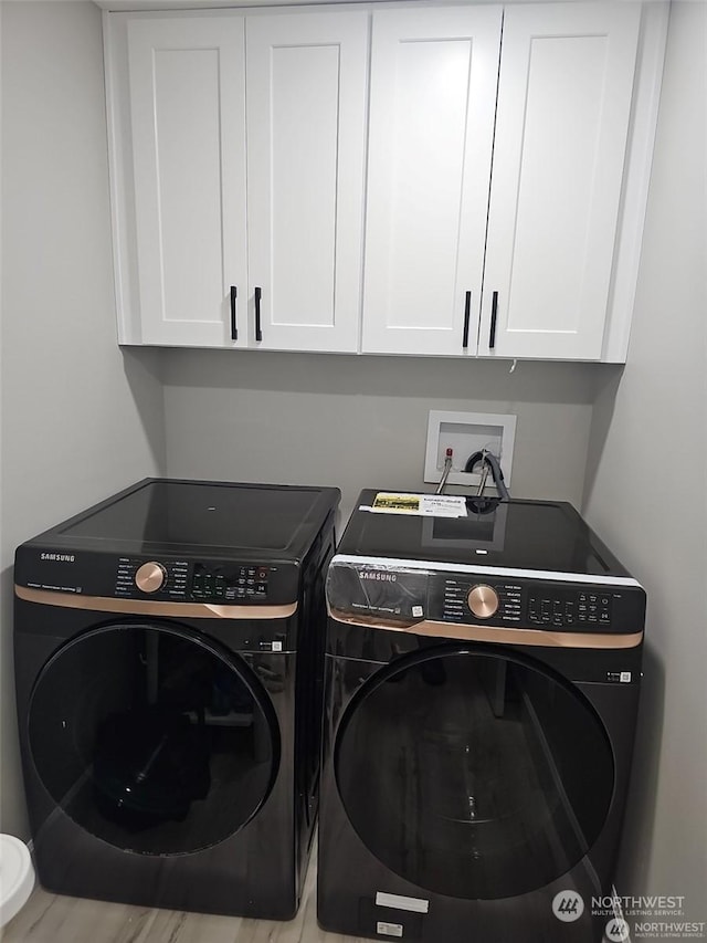 clothes washing area featuring washer and dryer and cabinets