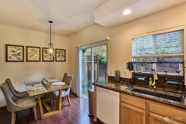 kitchen with dishwasher, sink, dark hardwood / wood-style flooring, dark stone counters, and decorative light fixtures