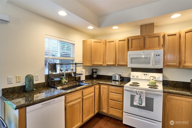 kitchen with dark hardwood / wood-style flooring, white appliances, dark stone countertops, and sink