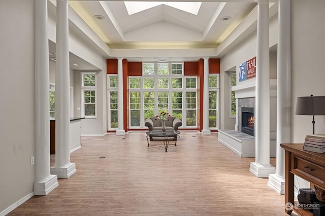 sunroom / solarium featuring vaulted ceiling with skylight, a raised ceiling, and a fireplace