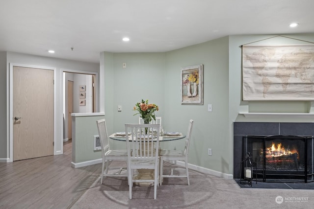 dining space featuring wood-type flooring and a tiled fireplace