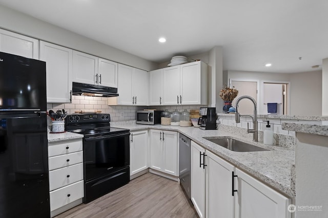 kitchen with black appliances, white cabinets, sink, light hardwood / wood-style flooring, and light stone countertops