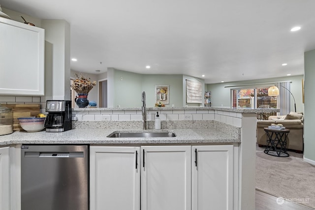 kitchen featuring dishwasher, white cabinetry, light stone countertops, and sink