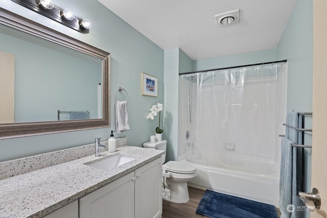 full bathroom featuring hardwood / wood-style floors, vanity, shower / bath combo, and toilet