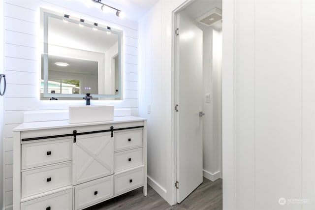 bathroom featuring wooden walls, hardwood / wood-style floors, and vanity