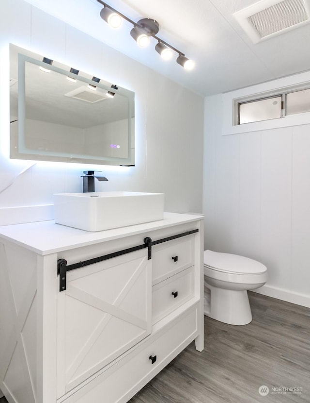 bathroom with hardwood / wood-style floors, vanity, and toilet