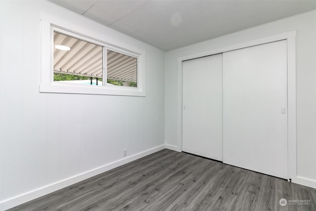 unfurnished bedroom with dark wood-type flooring and a closet