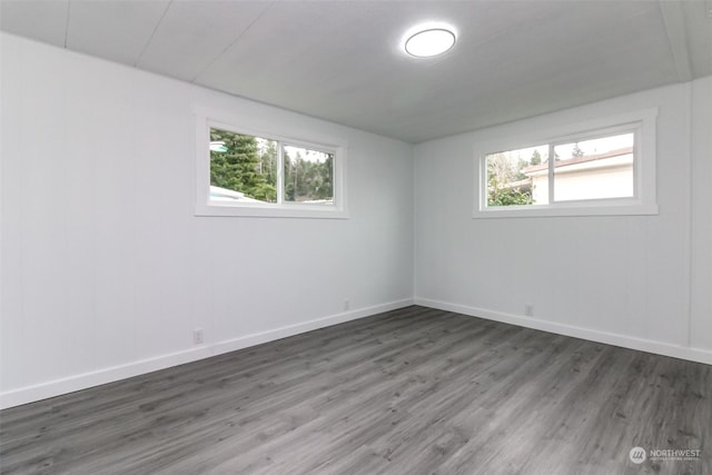 empty room with dark hardwood / wood-style floors and a healthy amount of sunlight