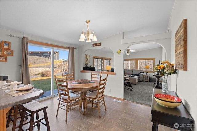 dining area featuring ceiling fan with notable chandelier