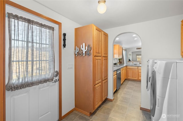 kitchen featuring stainless steel dishwasher, washer and clothes dryer, sink, and light brown cabinets