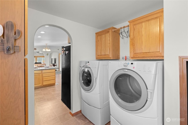 washroom featuring cabinets, light tile patterned floors, a chandelier, and washing machine and clothes dryer